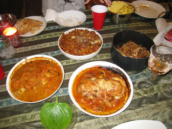 Overhead view of an Italian-style dinner spread with baked pasta and chicken cacciatore