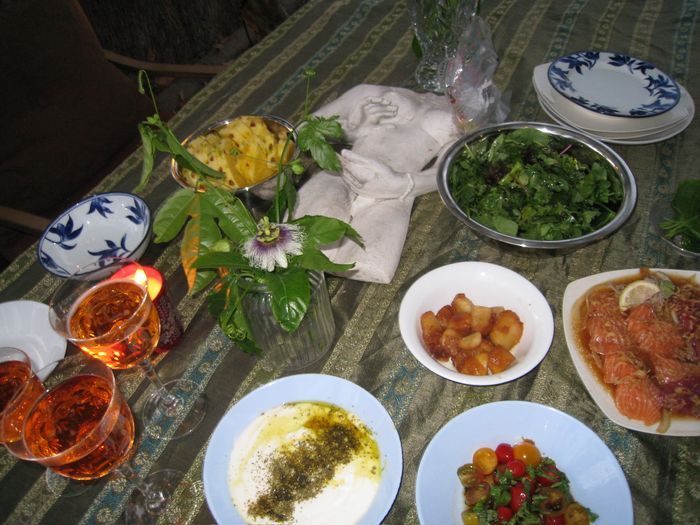 Overhead view of a summer dinner spread with salad, pineapple, salmon, and burrata