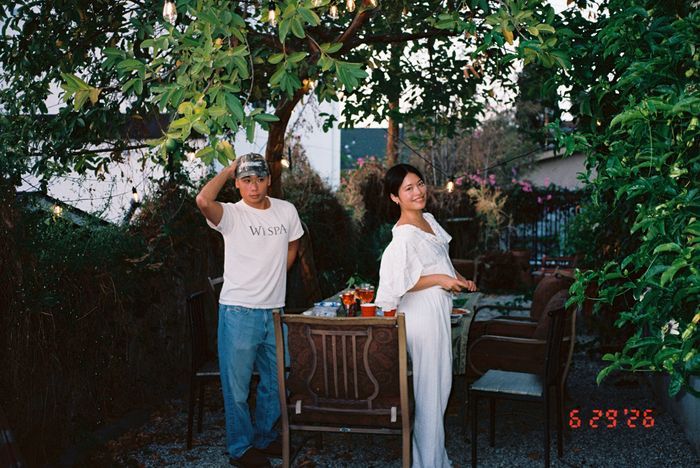 Two friends standing by a candlelit dinner table under string lights