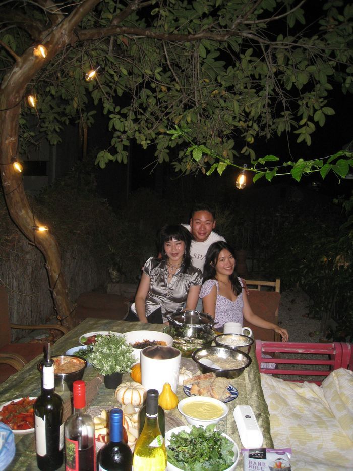 Three friends posing together at a candlelit outdoor dinner table