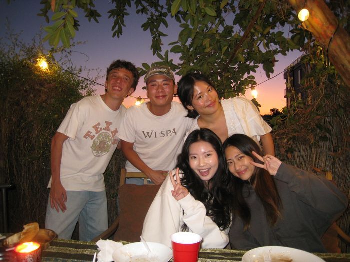 Group of friends smiling at an outdoor dinner table at dusk