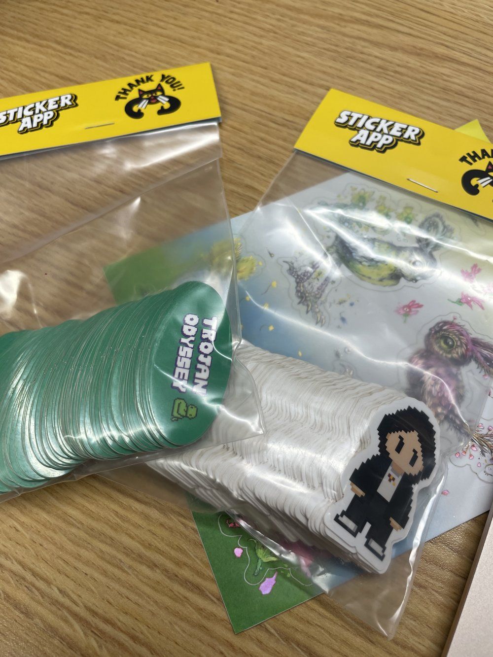 Physical Trojan Odyssey sticker packs featuring pixel art character and campus mascot designs